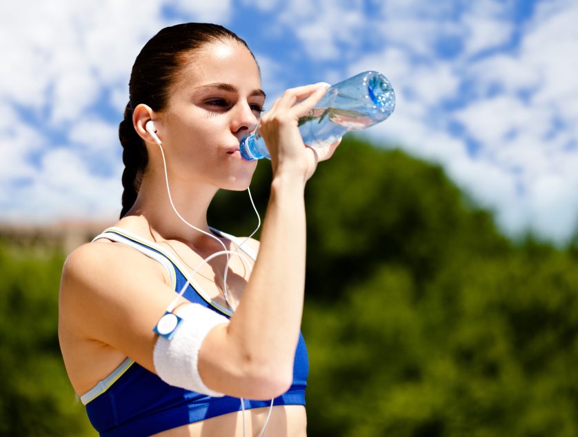 thirsty sporty woman drinking water after training